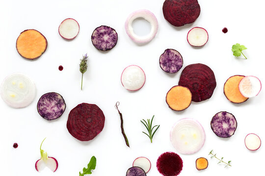 Rodajas de verduras moradas y amarillas sobre fondo blanco
