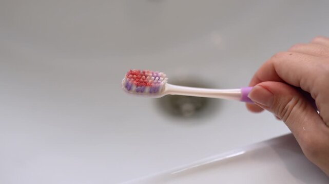 Young woman holds a toothbrush with visible blood on the bristles, illustrating gum bleeding after brushing and dental care problem