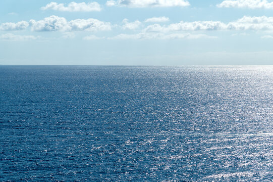 Expansive sea reflecting sunlight under cloudy sky horizon