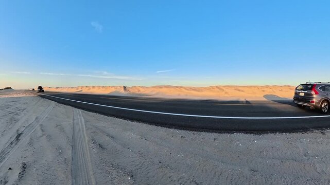 dune ridge forms the backdrop to moving road traffic in 4K video on a North Carolina coastal road
