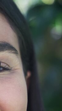 Vertical video: Opening eye, smiling, woman reacting to sun in leaves, eyelashes showing