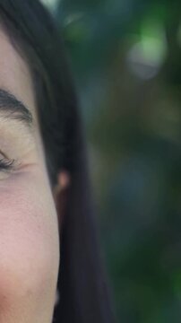 Vertical video: Reacting left woman squinting, smiling to garden sunlight, left eye seen