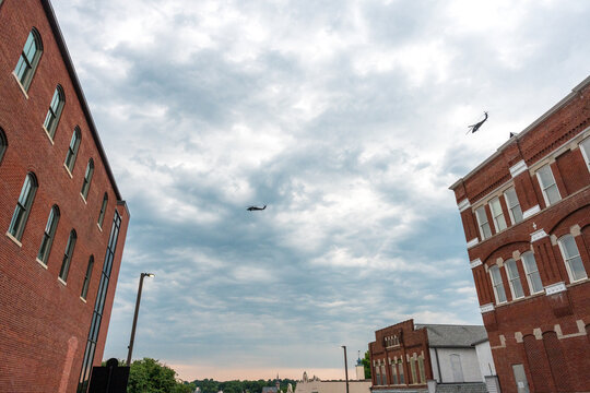 Military escort helicopters flying over brick buildings in Jefferson City, Missouri, July 2026