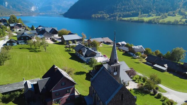 Aerial Drone Clockwise Orbit around Historic Church in Grundlsee with Traditional Alpine Houses and Beautiful Lake View in Austria