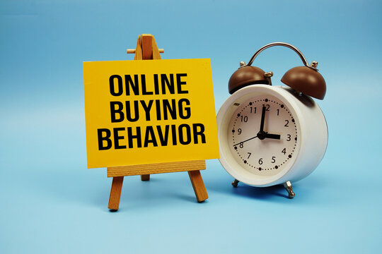 Online Buying Behavior text written on paper card and alarm clock on blue background
