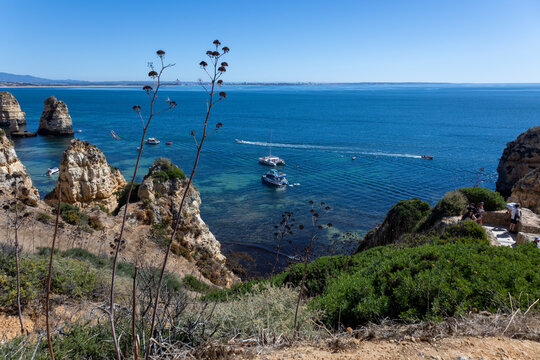 Boats anchored in turquoise bay below sandstone cliffs and sea stacks at Ponta da Piedade, Algarve, Portugal
