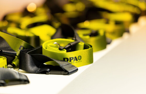 Amsterdam, Netherlands - September 11, 2026: Green branded lanyards with black clips arranged on a white surface in shallow focus, featuring visible DPA Microphones branding in a product detail