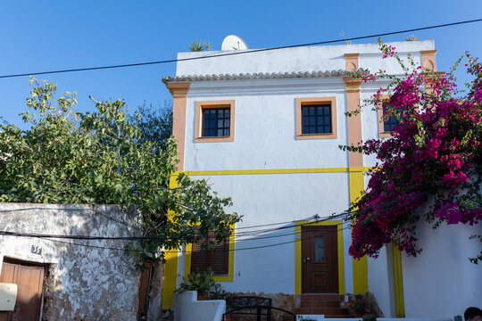 White house with yellow and orange trim and blooming bougainvillea in Ferragudo, Algarve, Portugal