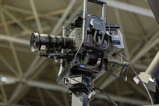 Amsterdam, Netherlands - September 11, 2026: Professional broadcast camera with zoom lens mounted on a support system beneath an exhibition hall ceiling at IBC