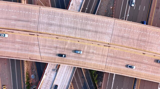 Slow descend on the wide concrete overpass over the multi-lane highway. Cars move quickly by the numerous roads.