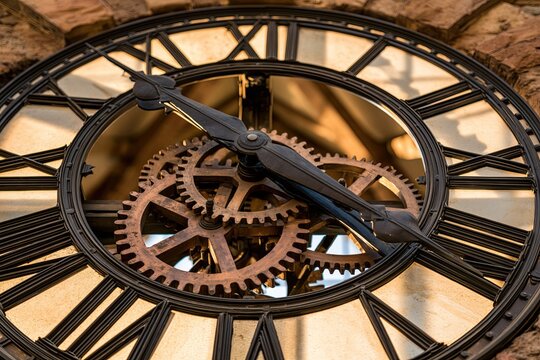 Close up view of the interior of a clock tower reveals intricate gears and clock hands moving highlighting the mechanics of timekeeping in the structure