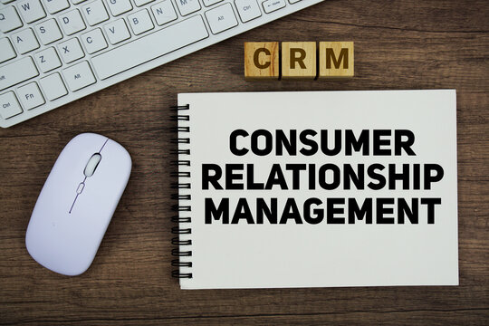 CRM Consumer Relationship Management message with keyboard and optical mouse on wooden background