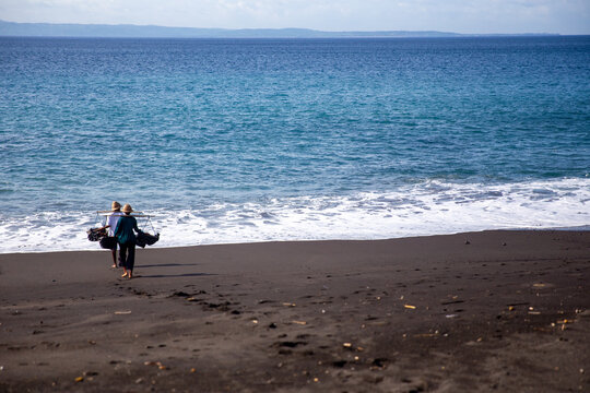 Balinese Salt Farmers Carrying Toke Baskets on Volcanic Black Sand Beach