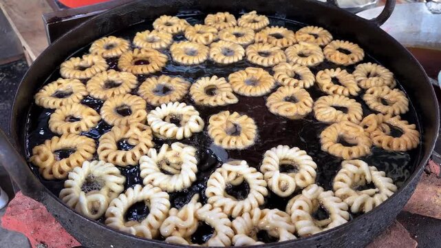 Fresh delicious indian imarti sweet ring dessert frying in hot oil 4k video footage