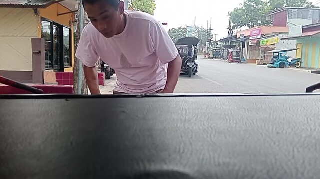 A driver waiting on a bentor motorized rickshaw for regular school shuttle service in Kotamobagu
