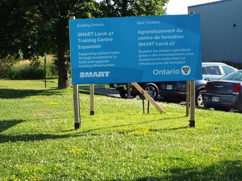 Gloucester, Ontario, Canada &ndash; August 1, 2026: A bilingual Ontario government and" SMART Local 47 construction sign" is posted on a grassy lawn with parked cars nearby on Green Creek Drive.