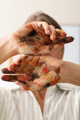 Creativity and artistic expression, woman showing hands covered in colorful paint for creative process, art therapy and self expression in home studio © Pixel-Shot