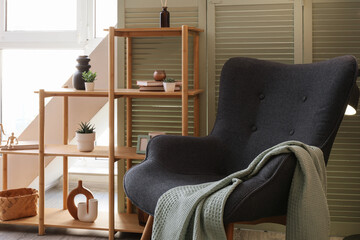 Home comfort and interior design, cozy reading nook with armchair and wooden shelving in a modern living room with soft natural light © Pixel-Shot