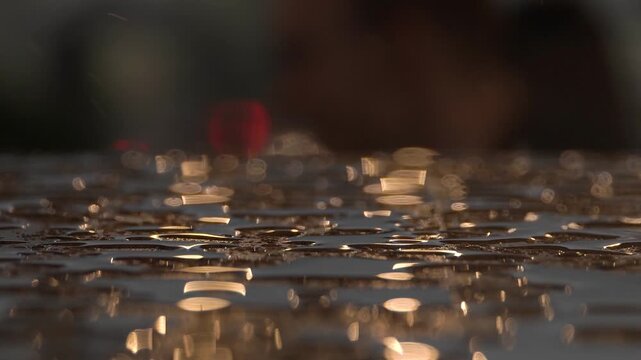 Sunset sunlight shines on transparent raindrops on a wooden surface, blurry background