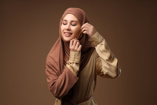 Modesty and empowerment, young woman wearing a brown hijab smiling with confidence and grace in a studio portrait with neutral background