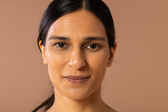 Indian woman posing in studio with neutral clothing against warm beige backdrop