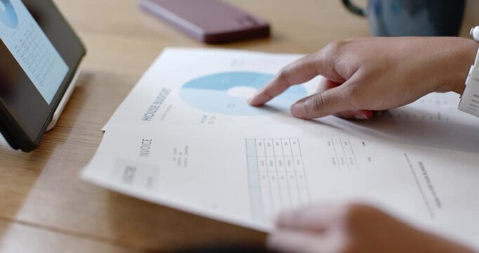 Right hand entering and tapping blue chart on desk, two fingers tracing chart and comparing numbers