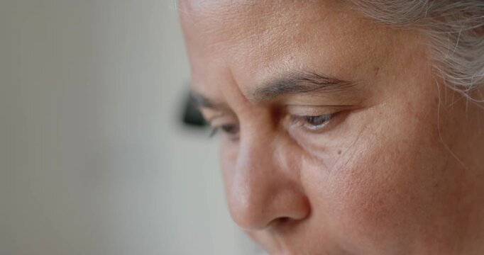 Mature African American woman lowering gaze, camera revealing face, lifting eyes at home near lamp