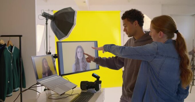 Diverse team reviewing captured portraits on monitors in studio, pointing at DSLR, tweaking framing
