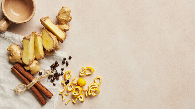 Fresh ginger root slices and lemon peel curls on pale travertine, copy space