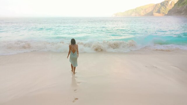 Woman in Light Blue Dress Walking Toward Ocean Waves at Kelingking