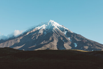 Magnificent scenic view of the snow covered Koryaksky stratovolcano rising into a clear blue sky over Kamchatka Krai, showcasing wild volcanic alpine terrain in Russia © TravelFlow