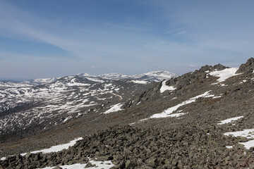 Panoramic view of rugged rocky slopes and snow patches on Mount Konzhakovsky Kamen under a clear blue sky in Sverdlovsk Oblast, Russia during bright spring season © TravelFlow