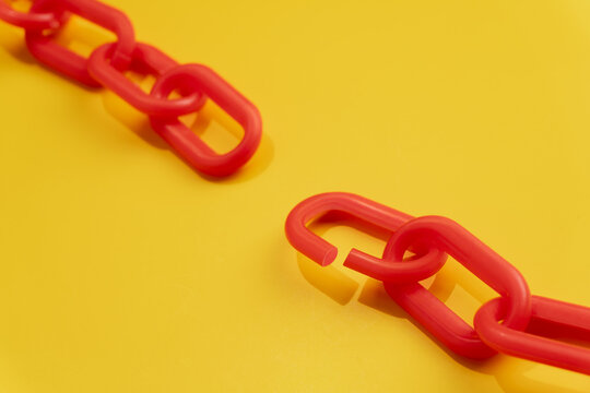 Red chain links separated on a yellow background. Supply chain failure, breach, disconnection, separation, system collapse concept.