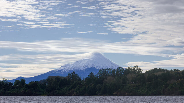 Panoramic landscape of snow-covered Osorno Volcano rising above the forested shores of Lake Llanquihue near Puerto Varas, Chile