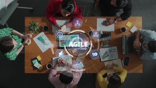 Aerial view of a diverse team engaged in an agile meeting, featuring brainstorming, planning, and collaborating with charts, laptops, and notes on a wooden table. Raster