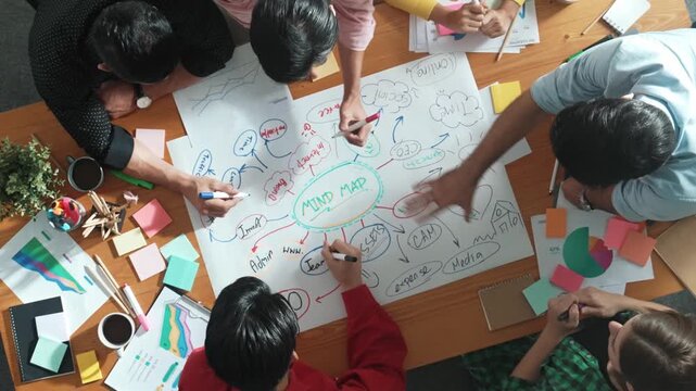 Group of business people writing and making mind map to brainstorming marketing idea at meeting. Top aerial view of investors sharing plan or strategy by using sticky notes and marker. Convocation.