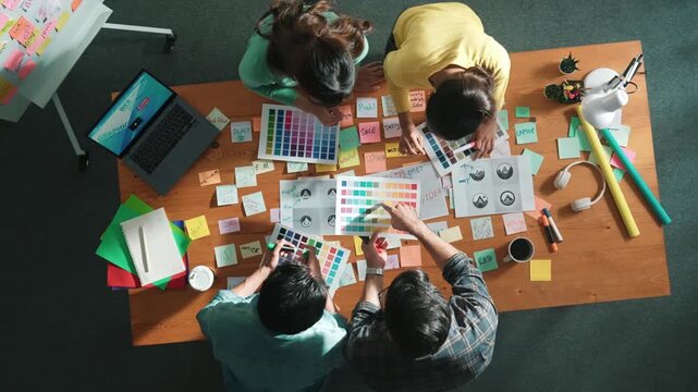 Top view of smart manager holding and looking at color palettes and choose color for logo or product. Aerial view of business team working together brainstorm appropriate theme for project. Symposium.