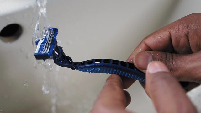 Cleaning a blue toothbrush under running water at a sink