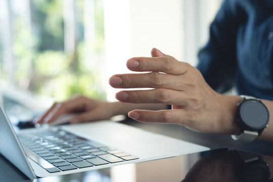 Close-up of woman hand gesturing while working on laptop in modern office, business communication, online meeting concept.