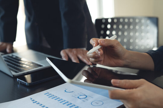 Close-up of businesswoman using stylus on digital tablet during meeting with colleague in office, modern technology and collaboration concept.