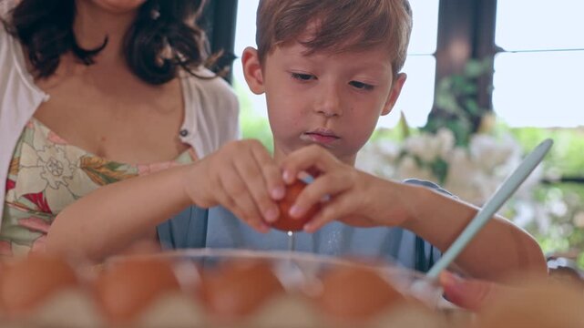 Boy Learning Egg Cooking in Kitchen with Adult Woman, Child and Family Preparing Food Together Through Warm, Focused Home Baking Moment