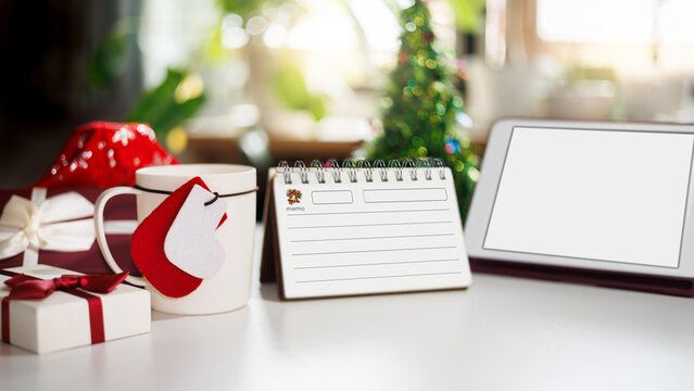 close-up shot, white coffee cup with christmas item and gift box, tablet on table, diary for new year's greetings message, celebration for new year 2027 concept