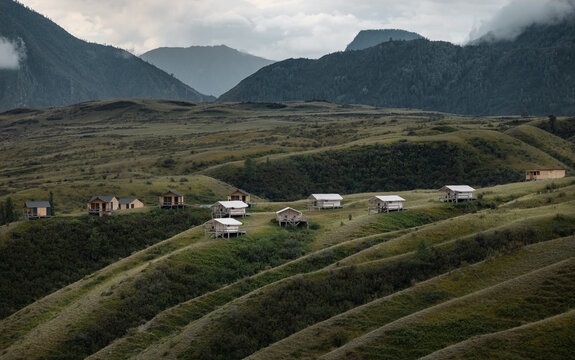 Modern glamping campsite in the Altai mountains. Safari tents and cabins on green hills of the Altai Republic, Russia. Concept of ecotourism, domestic travel and Siberian wilderness.