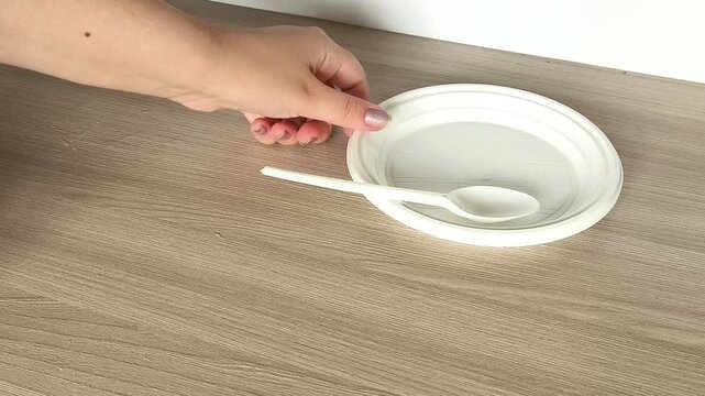 Woman setting out single-use plastic dishes on a table, illustrating convenient food service, household use and everyday dining preparation.