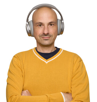 A smiling bald man is listening to music through headphones