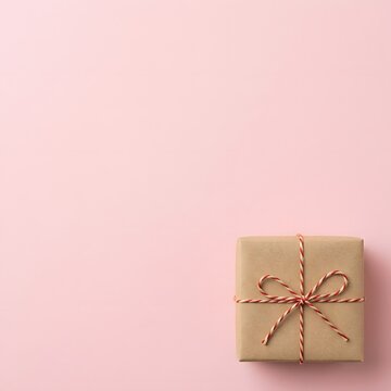 Kraft paper gift box tied with red and white twine on pink background