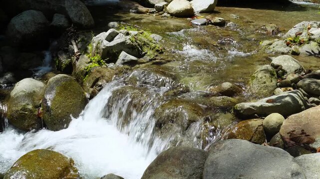 Crystal Clear Tropical Waterfall Flowing Across River Rocks 4K