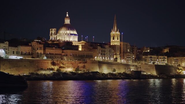 Silhouette of the Gozo Fast Ferry (Valletta - Gozo) passes in front of a nightscape of Valletta Capital City in Malta. 