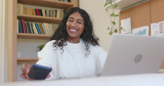 African American woman responding to online call in home office, typing on laptop