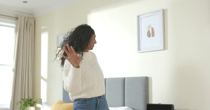 African American woman dancing to music in bedroom, moving to turntable, playing vinyl record